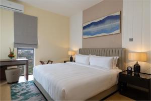 a bedroom with a large white bed and a window at Pan Pacific Serviced Suites Nairobi in Nairobi