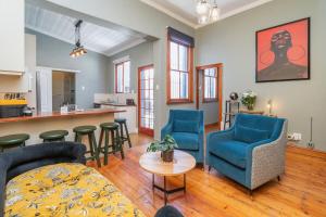 sala de estar con 2 sillas azules y mesa en Elegant Home Nestled in a Serene Suburban Setting en Ciudad del Cabo