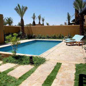 una piscina en un patio con un banco y palmeras en Aseel Resort, en Riad