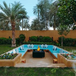 a patio with blue couches and a fire pit at Aseel Resort in Riyadh