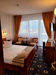 a hotel room with a bed and a desk and window at Hotel Belvedere in Cluj-Napoca