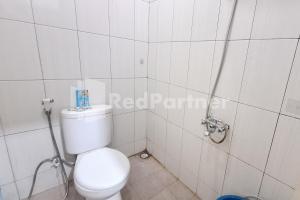 a bathroom with a white toilet and a shower at De Peppzzz near UGM Yogyakarta RedPartner in Kejayan