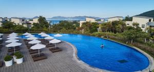 a swimming pool with umbrellas and chairs and a person in a pool at Ananti at Namhae in Namhae