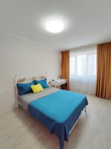 1 dormitorio con 1 cama grande con almohadas azules y amarillas en Аккуратная 1-комнатная квартира в ЖК Nomad, en Almaty