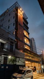 雅加達的住宿－Grand Ametis Hotel Jakarta，停在高楼前的汽车
