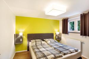 een slaapkamer met een bed en een gele muur bij Ferienwohnung im Eichholz in Arnsberg