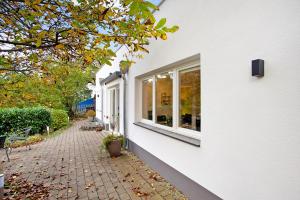 a white house with a brick sidewalk next to a window at Ferienwohnung im Eichholz in Arnsberg