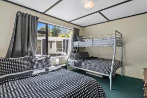 two bunk beds in a room with a window at Coastal Charm - Picton Holiday Home in Picton