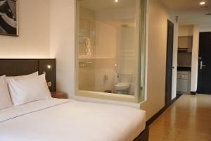 a bedroom with a large white bed and a bathroom at Lemansion Senopati in Jakarta