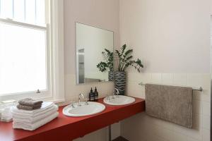 a bathroom with two sinks and a mirror at The Bank Main Street Apartment in West Wyalong