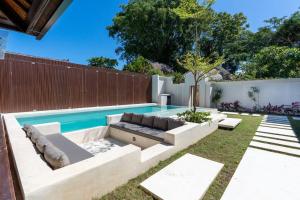Un patio trasero con piscina con un sofá y una piscina. en Green Jimbaran Bay Villa II, en Jimbaran