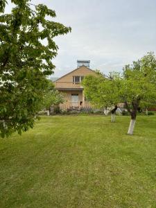 a house in a field with trees in the foreground at Chkalovka guest house with Sevan view in Sevan