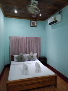 Schlafzimmer mit einem Bett mit weißer Bettwäsche und Kissen in der Unterkunft Phanh Tha Sone House in Luang Prabang