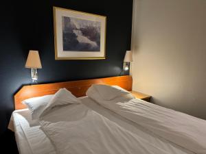 a bedroom with a bed with white sheets and pillows at Notodden Hotel in Notodden