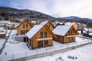 a group of wooden homes in the snow at Apartament Liściasty 1 z tarasem - Dream Apart in Ustroń