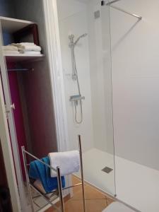 een douche met een glazen deur en een stoel in de badkamer bij maison dans jardin in Torreilles