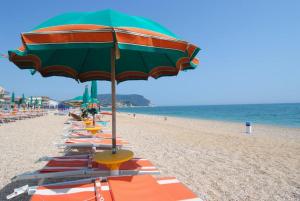 una fila de sillas y sombrillas en una playa en RS304 - Marcelli, nuovo bilo fronte mare con spiaggia inclusa, en Marcelli