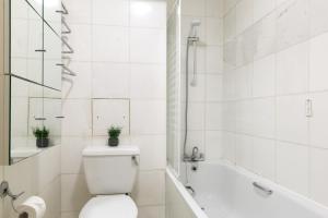 a white bathroom with a toilet and a bath tub at The Aldgate Flat in London