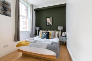 a bedroom with a large bed and a green wall at The Aldgate Flat in London