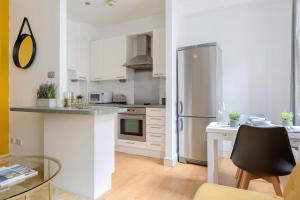 a kitchen with white cabinets and a stainless steel refrigerator at The Aldgate Flats in London