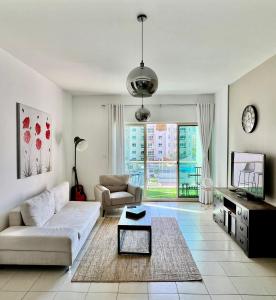 a living room with a couch and a tv at Vanilla latte 1bedroom Apt @the Greens in Dubai
