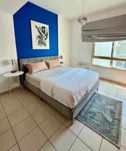 a bedroom with a large bed with a blue wall at Vanilla latte 1bedroom Apt @the Greens in Dubai
