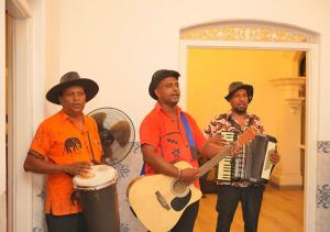 un grupo de tres hombres con camisas naranjas tocando instrumentos en Villa Fernando Resort en Chilaw