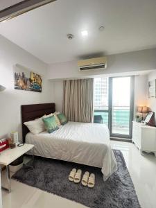 a bedroom with a bed and a table and a window at Sakura apartment in Manila