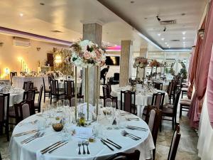 a dining room with tables with white tablecloths and flowers at Sofia in Călăraşi