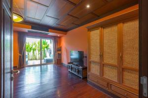 a living room with a flat screen tv and a room with orange walls at 7 Bedrooms Mansion on The Golf Course! JB2 in Hua Hin