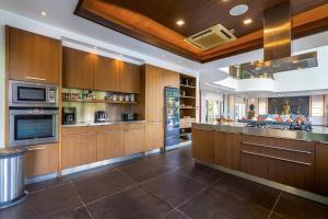 a large kitchen with wooden cabinets and stainless steel appliances at 7 Bedrooms Mansion on The Golf Course! JB2 in Hua Hin