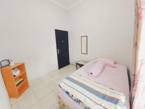 um pequeno quarto com uma cama e uma mesa de cabeceira em Rumah Lavender near OPI Mall Jakabaring em Palimbão