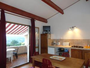 uma cozinha e sala de jantar com uma mesa e uma varanda em Colocha em Cargèse