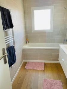 uma casa de banho com uma banheira, um lavatório e uma janela em Agréable T3 - 70m2 avec petite terrasse em Granges-lès-Valence