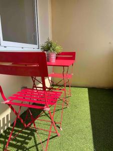 três cadeiras vermelhas e uma mesa vermelha com um vaso de plantas em Agréable T3 - 70m2 avec petite terrasse em Granges-lès-Valence