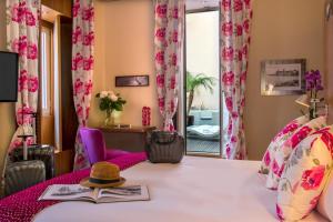 Habitación con cama con sombrero y libro en Hotel Beau Rivage en Niza