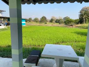 una mesa de picnic y un banco frente a un campo en Srihome ยายศรีโฮมแอนแคมป์ปิ้ง en Ban Don Tum (1)