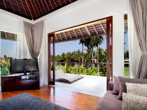 a living room with a television and a balcony at Villa Kalyani in Canggu