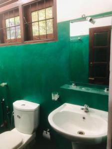 baño verde con aseo y lavamanos en Laughing Jungle Unawatuna, en Galle