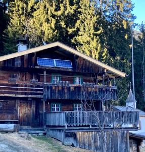 uma cabana de madeira com um alpendre e painéis solares em Goass'n Alm Zillertal em Hippach