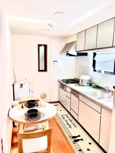 una cocina con armarios blancos y una mesa pequeña. en 吉吉の家, en Tokio