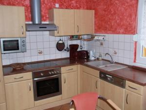 kuchnia z drewnianymi szafkami i czerwoną ścianą w obiekcie Ferienhaus Sonnenschein in Baabe w mieście Baabe