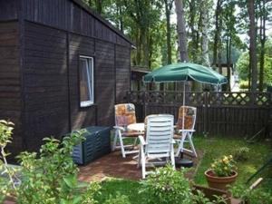 eine Terrasse mit einem Tisch, Stühlen und einem Sonnenschirm in der Unterkunft Bungalow mit Terrasse in Glowe