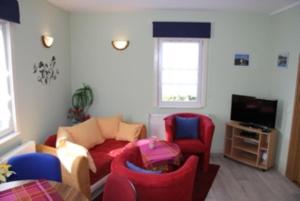 ein Wohnzimmer mit roten und blauen Stühlen und einer Couch in der Unterkunft Bungalow mit Terrasse in Glowe