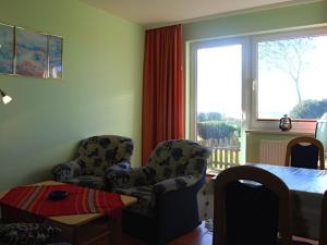 ein Wohnzimmer mit 2 Stühlen, einem Tisch und einem Fenster in der Unterkunft Ferienwohnung Rügen mit Ostseeblick in Dranske
