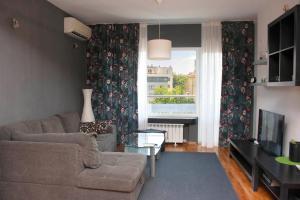 un soggiorno con divano, TV e finestra di Sunny Central Apartment a Sofia