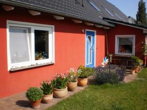 ein rotes Haus mit Topfpflanzen davor in der Unterkunft Ferienwohnung auf Rügen in Maltzien in Losentitz