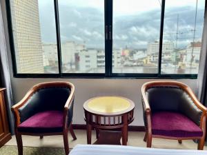 dwa krzesła i stół w pokoju z oknem w obiekcie Asian Hotel w mieście Hat Yai