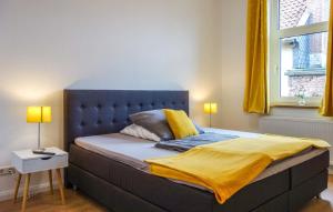 Una cama con cabecero azul y una manta amarilla. en Zur Ziegenmühle, en Lehrte