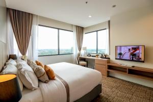 a hotel room with a large bed and a flat screen tv at Grand Fortune Hotel Nakhon Si Thammarat in Nakhon Si Thammarat